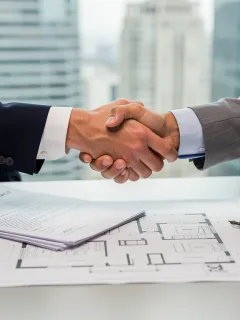 Professionals shaking hands over real estate documents, symbolizing new disclosure requirements in 2026.